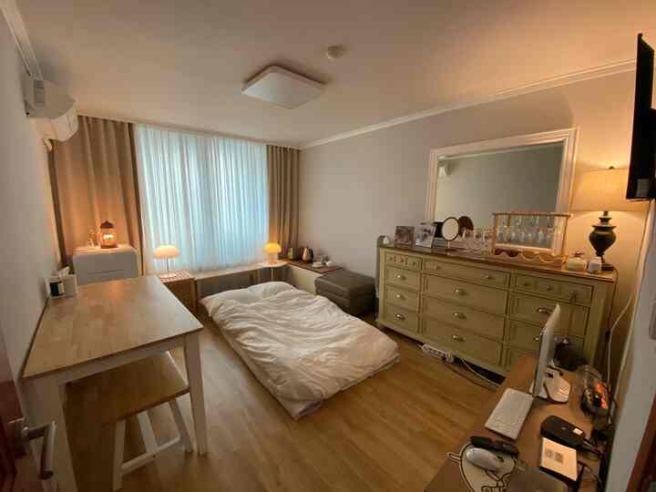 Ivory and beige toned multi-room featuring curtains and table lamps by the window, dresser and home cafe elements on the right, cozy atmosphere