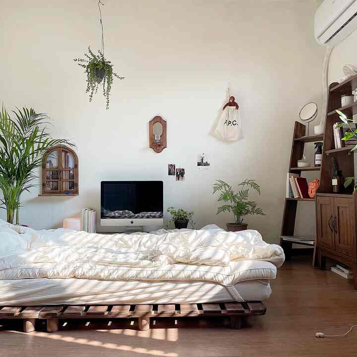White and wood-tone 6 tatami bedroom featuring wooden bed frame and various plants with a natural and calm atmosphere