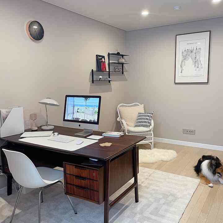Light brown toned study room featuring a mid-century modern desk and chair, wall shelves, and framed artwork creating a cozy remote work space
