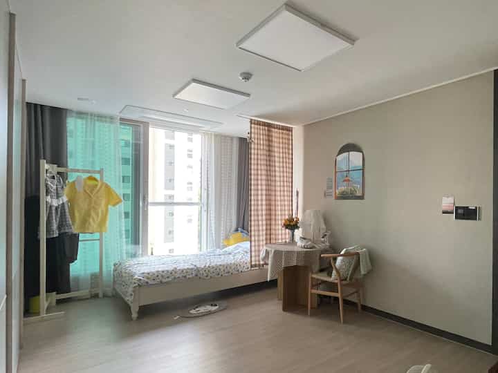 Natural tone 6-tatami bedroom with white walls, featuring baby clothes rack by the window and round table creating cozy atmosphere