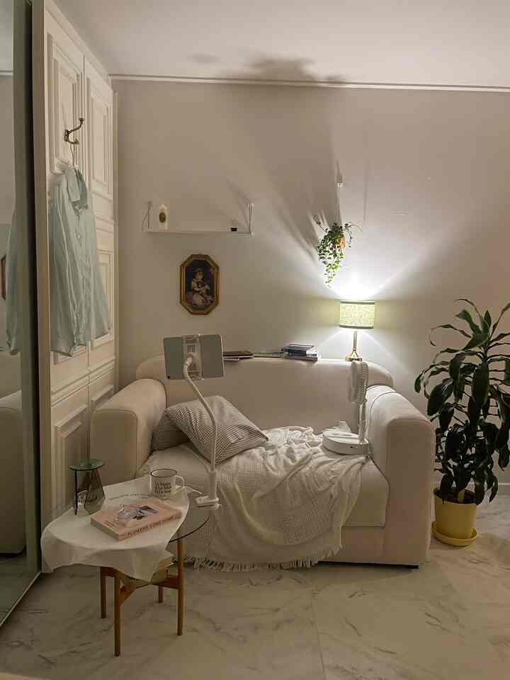 Natural-toned living room featuring a comfortable white sofa, greenery, and harmonious lighting in a minimalistic style