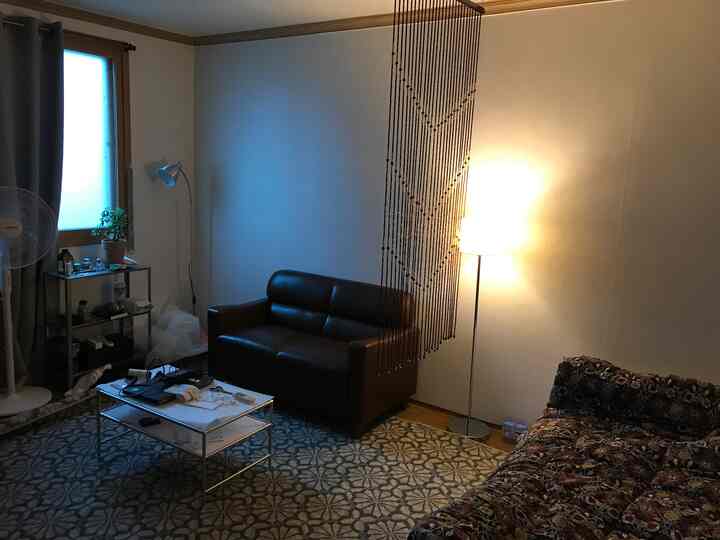 Modern living room with brown leather sofa and dark curtains, cozy lighting and patterned rug creating warm atmosphere