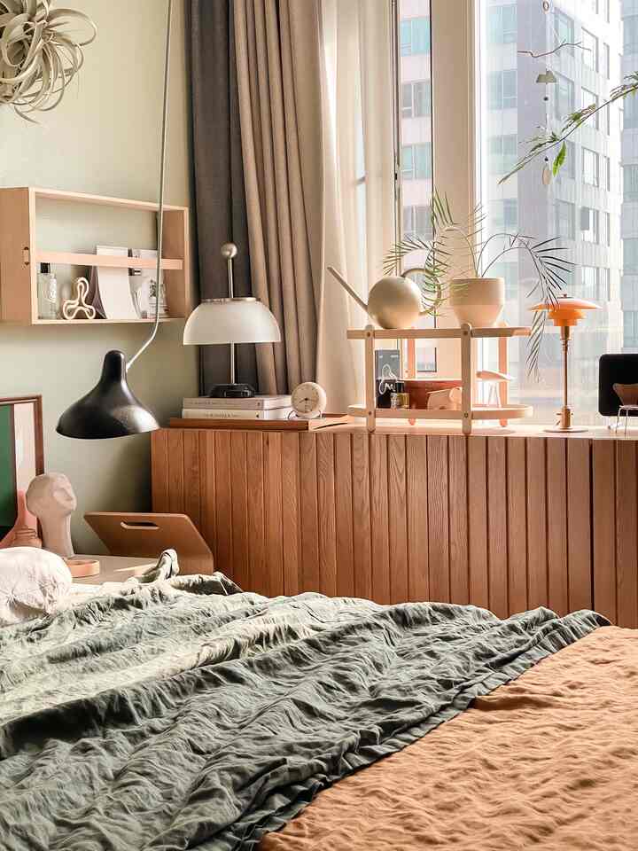 Sunlit bedroom in natural wood tones and green bedding, featuring three lighting fixtures adding warmth