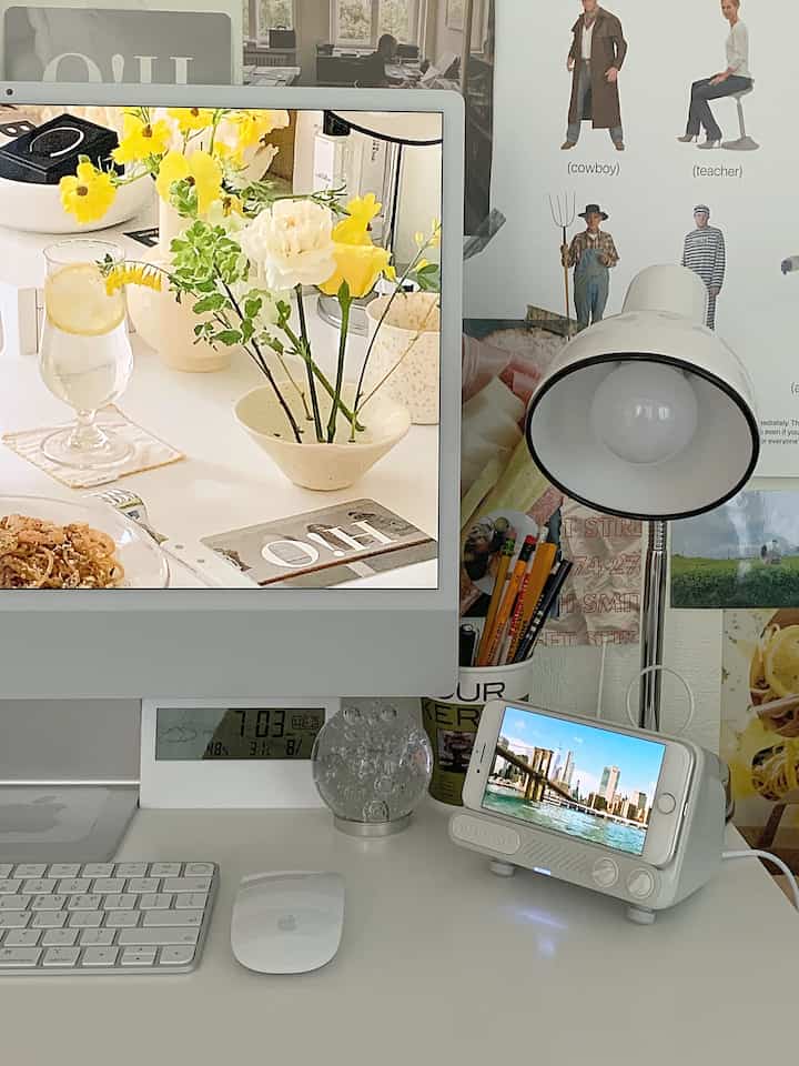 White and silver toned home office featuring a desk, monitor, and table lamp in a clean remote work setup
