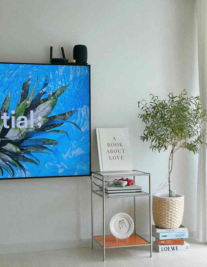 White and natural toned living room featuring a wall-mounted TV and a modular shelf with a PlayStation setup, clean and minimalistic space