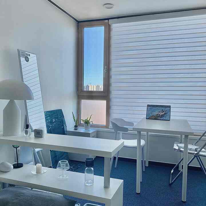 白と青のトーンのワンルーム、窓辺にデスクとブラインドが配置された爽やかで整ったホームオフィスの雰囲気