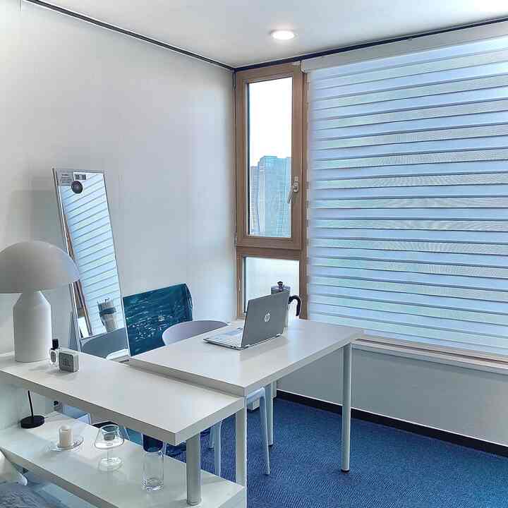 White and blue toned home office space featuring L-shaped desks and minimal furniture with a clean, bright atmosphere