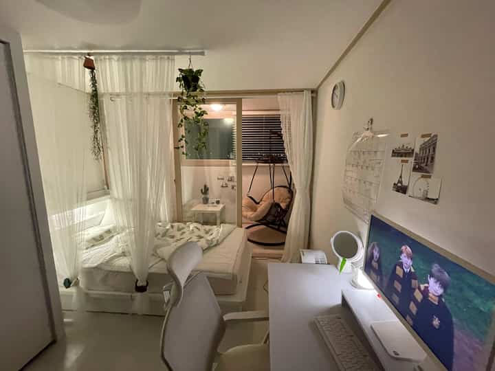 White-toned compact single bedroom featuring a desk and office chair in a simple home office setup