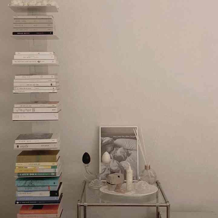 Beige and white toned study space featuring stacked books, candles on a transparent table, with a modern and calm atmosphere