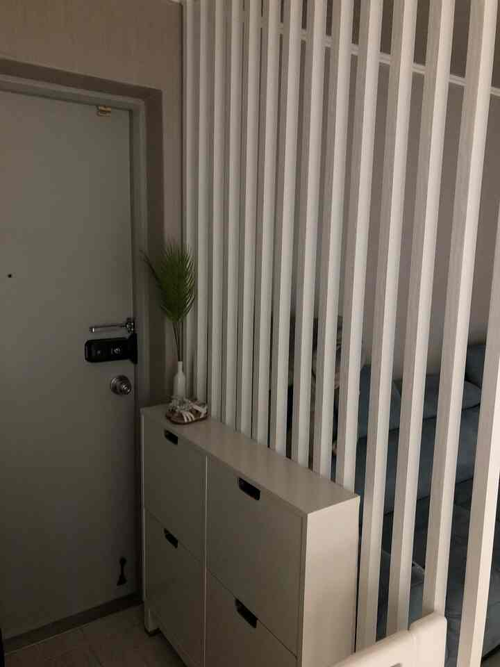 White-toned entrance space featuring a shoe cabinet and vertical slat room divider, creating a clean interior look