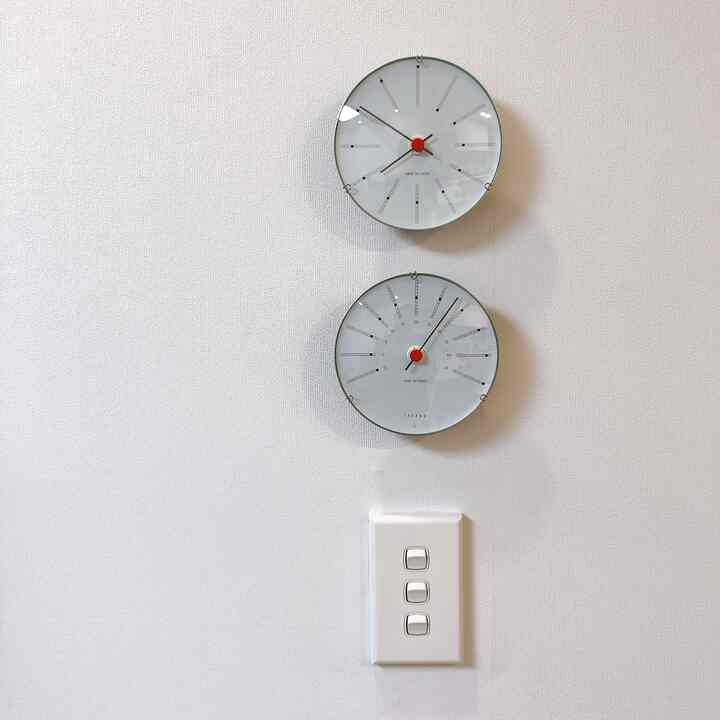 A simple living room interior featuring Arne Jacobsen clocks and Legrand switches on a white wall