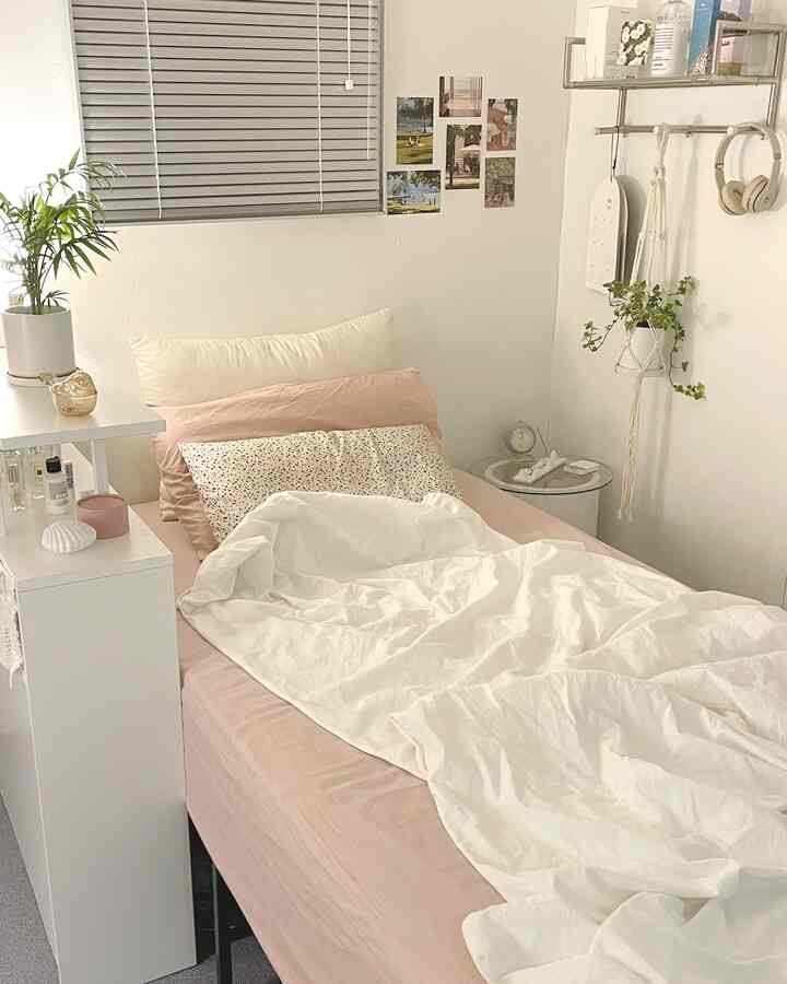 白とベージュのトーンの寝室、暖かい布団と植物が配置された居心地のよい一人暮らしの部屋