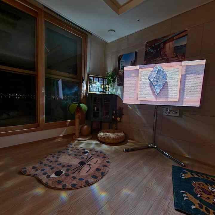 暖かみのある木目調のリビング、キャットタワーと動物柄のラグが配置された雰囲気のある空間