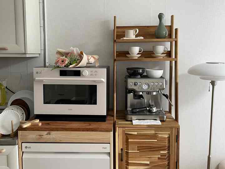 White and wood tone kitchen space featuring LG Objet appliances and a coffee machine, creating a clean and minimal home cafe interior