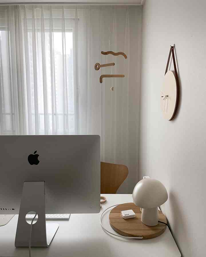 白と木目調が調和したモダンなホームオフィス、広いカーテンと壁掛け時計が配置されたすっきりとしたデスク環境