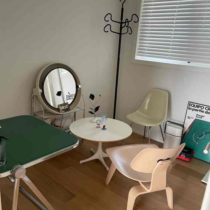 White and brown toned living room featuring a round coffee table, lounge chair, and metal coat rack in a clean layout