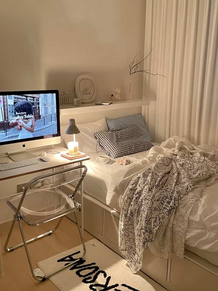White and wood-tone single household bedroom with a computer desk and transparent chair, showcasing a simple modern design