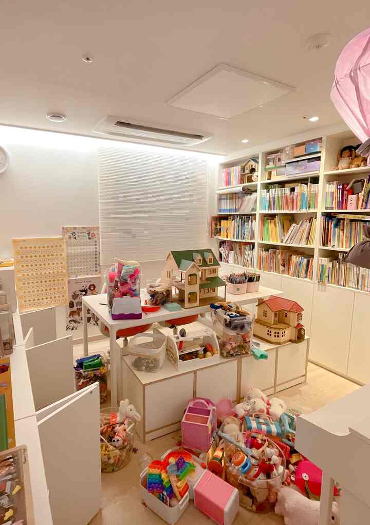 白とナチュラルカラーの子供部屋、整理された本棚とおもちゃ収納が配置された雰囲気のあるインテリア