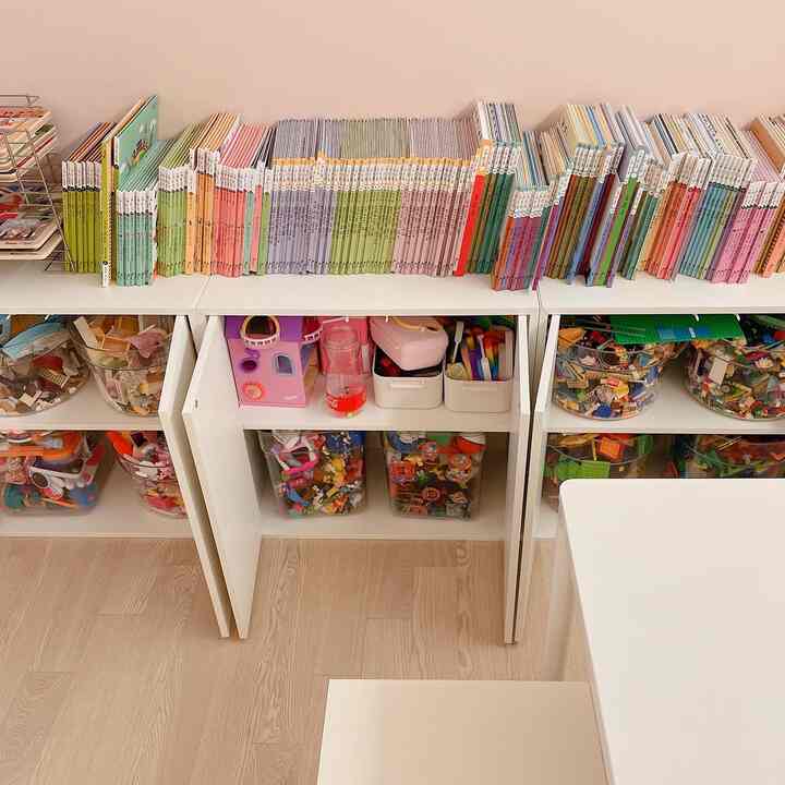 白と木目調の調和した子供部屋、整理された本棚と透明なおもちゃ収納が際立つ、清潔感ある空間