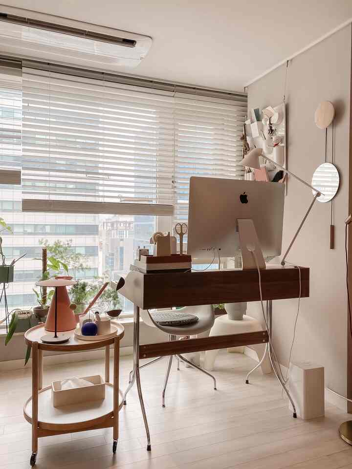 Bright white-toned room with wood-tone desk featuring an iMac computer in a clean home office setting