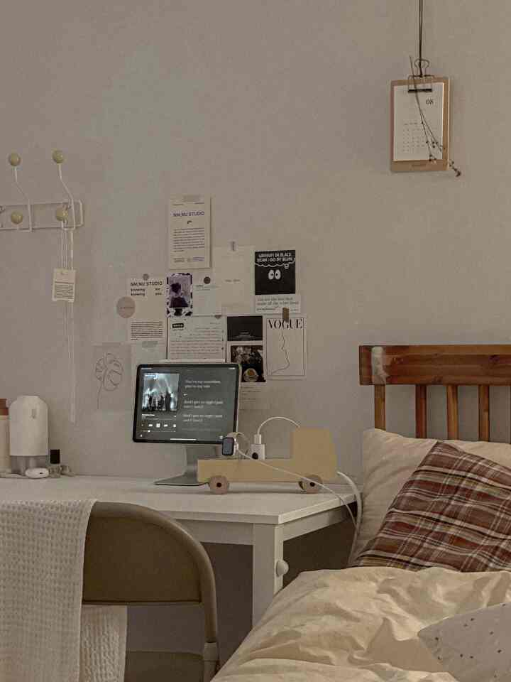 Beige and wood-tone bedroom workspace featuring a desk with iPad and wall decor, creating a cozy natural interior