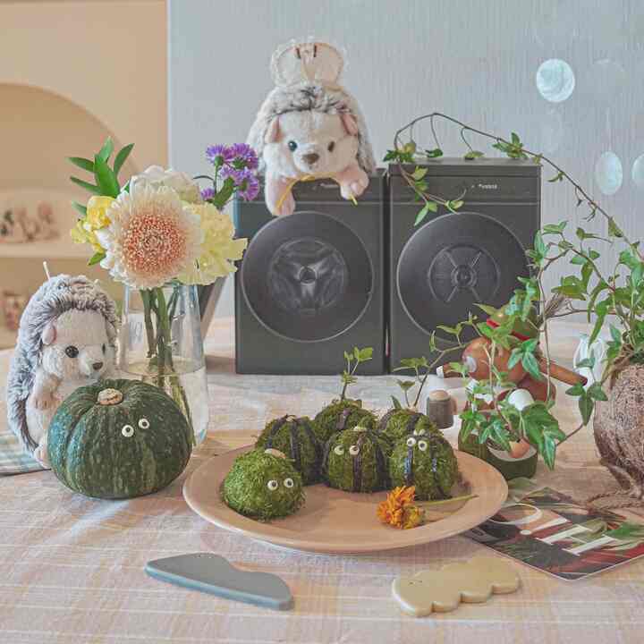 A cozy kitchen scene with white and beige tones featuring a dining table adorned with flowers, plants, and cute decorative items