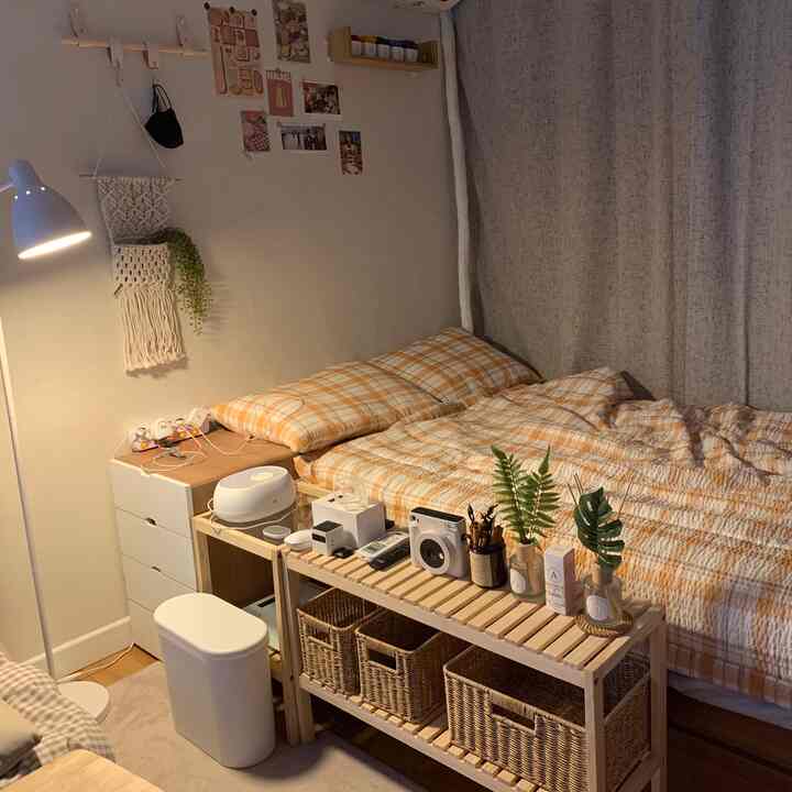 温かみのあるベージュとホワイトのトーンの寝室、チェック柄の寝具と木製シェルフが配置された雰囲気のある空間