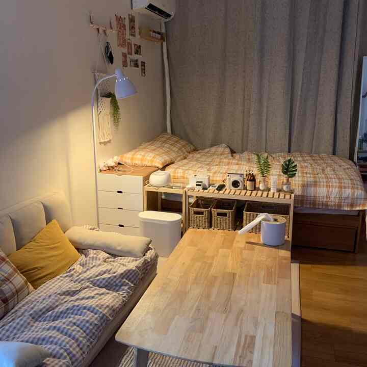 アイボリーの壁と木目調家具が調和するワンルーム寝室、ソファとコーヒーテーブルが落ち着いた雰囲気を演出