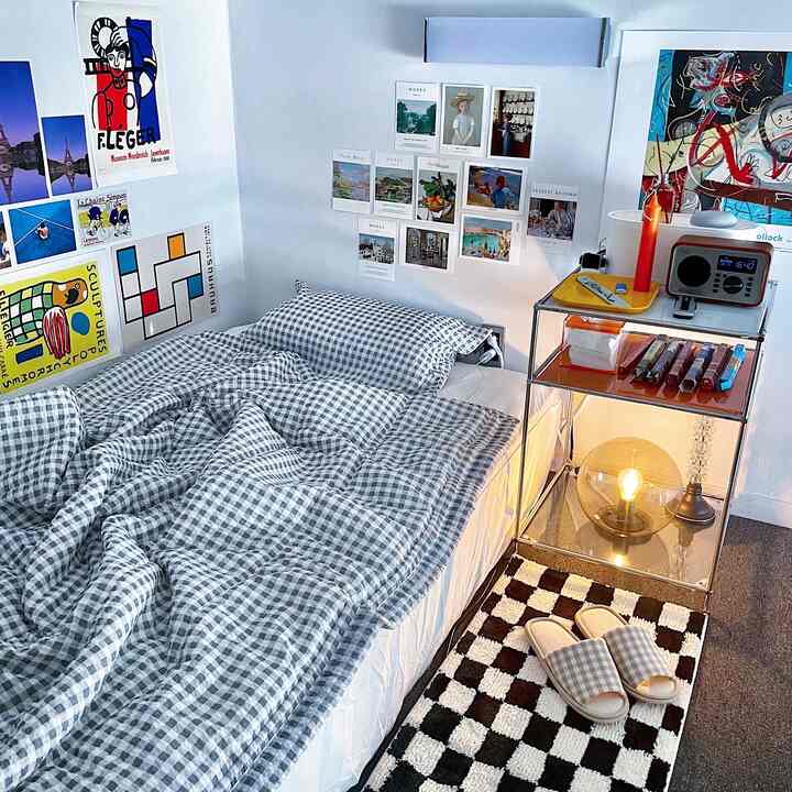 白とグレーのトーンが特徴の6畳寝室、ベッドとメタルのナイトテーブル、ポスターが配置された雰囲気あるナチュラルモダン空間