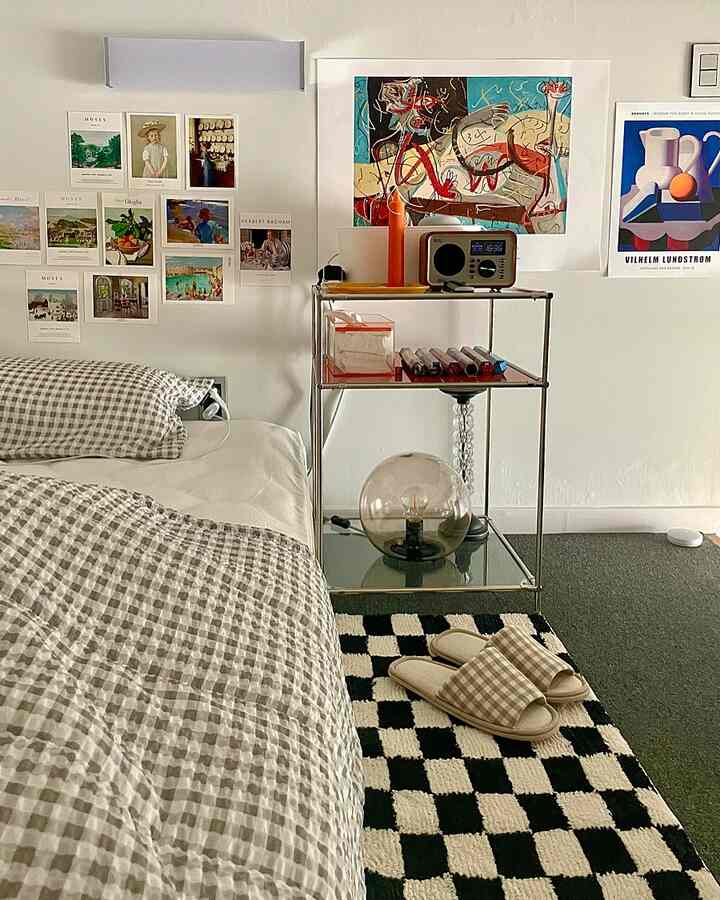 Natural-tone bedroom featuring gingham bedding and slippers, metal shelving unit and wall art creating a cozy atmosphere