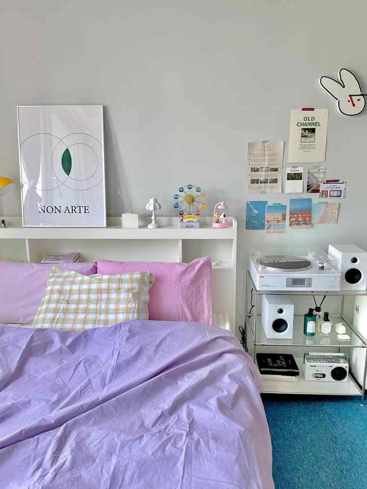 Modern bedroom with light gray walls and purple bedding, featuring an LP turntable and charming decorations