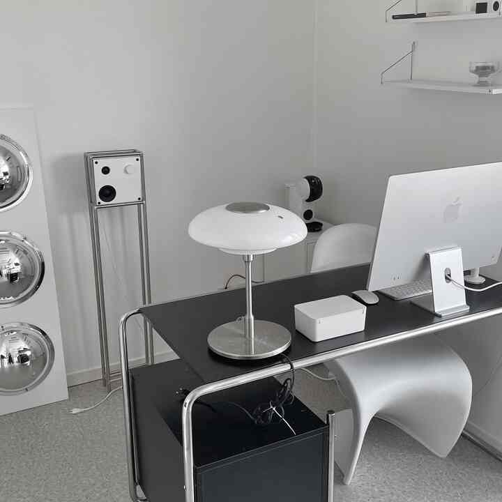 白と黒のトーンのワンルームホームオフィス、モダンなデスクとオフィスチェア、テーブルランプが整った作業環境を演出