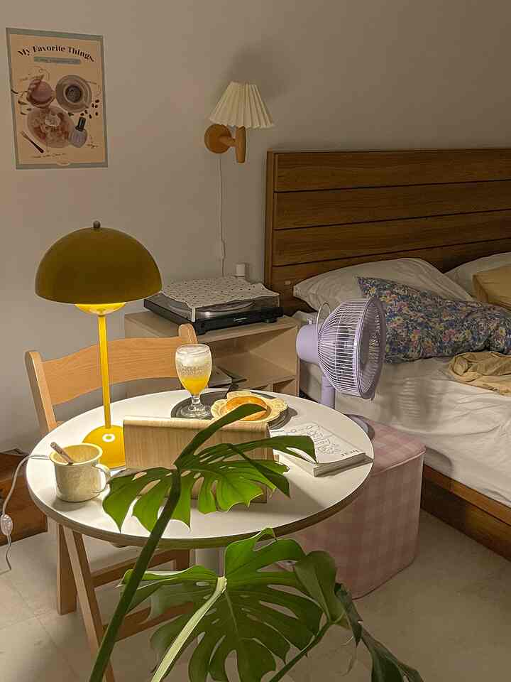 Natural brown and white bedroom featuring a round table with a stool and a table lamp, creating a warm atmosphere