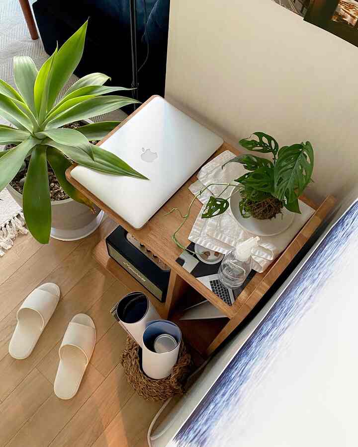 Wood tone and white small home office space featuring side table with laptop and plants in a neat atmosphere