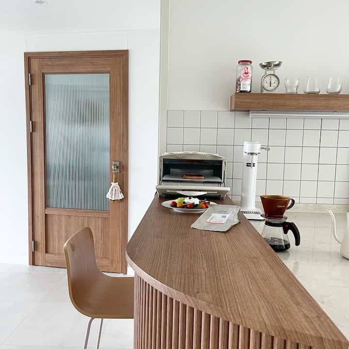 ナチュラルなブラウンウッドのキッチンホームバーと玄関の中門が調和した清潔で居心地の良い空間