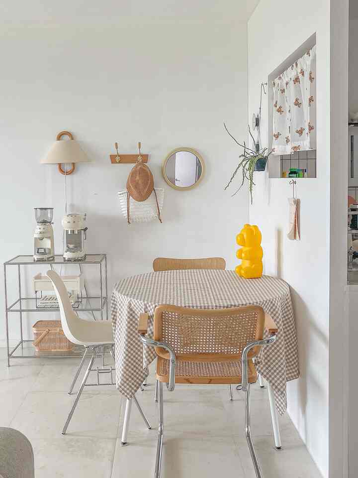 白と茶色のトーンが印象的な子供部屋、チェック模様のテーブルクロスと円形テーブルが配置された雰囲気のあるインテリア