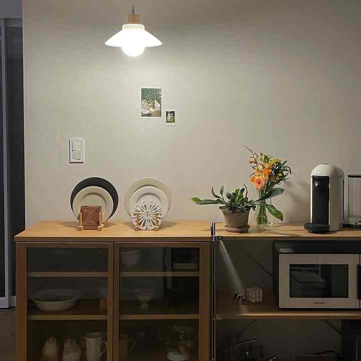 Natural wood-toned kitchen with white wall, neatly organized cabinet and coffee machine create a cozy atmosphere