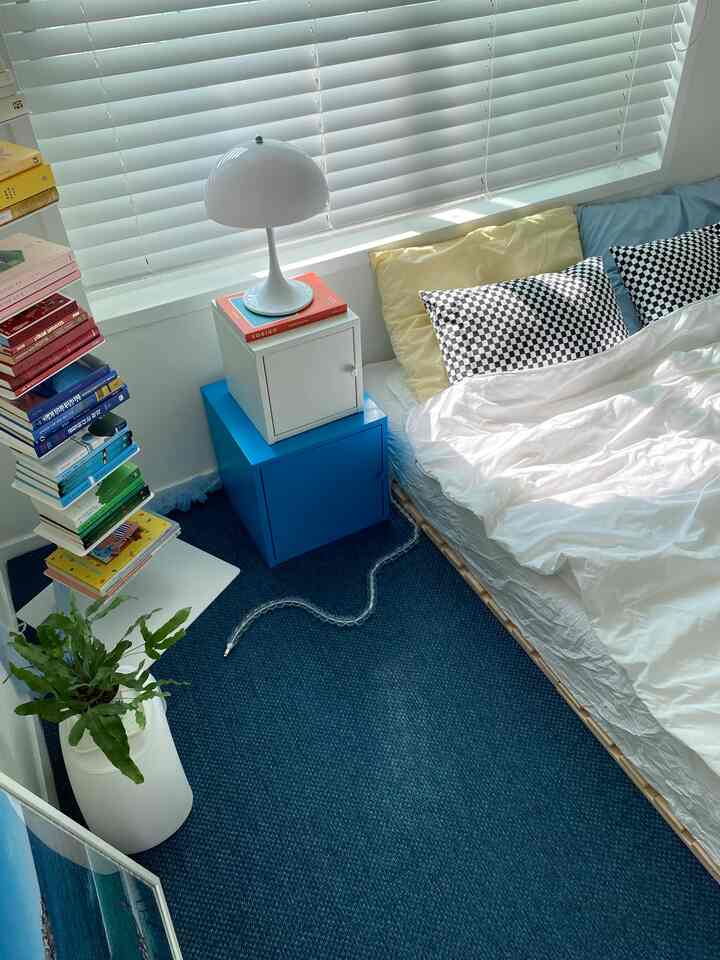 Cozy blue and white toned bedroom featuring a bed with pillows and storage cubes in a compact space