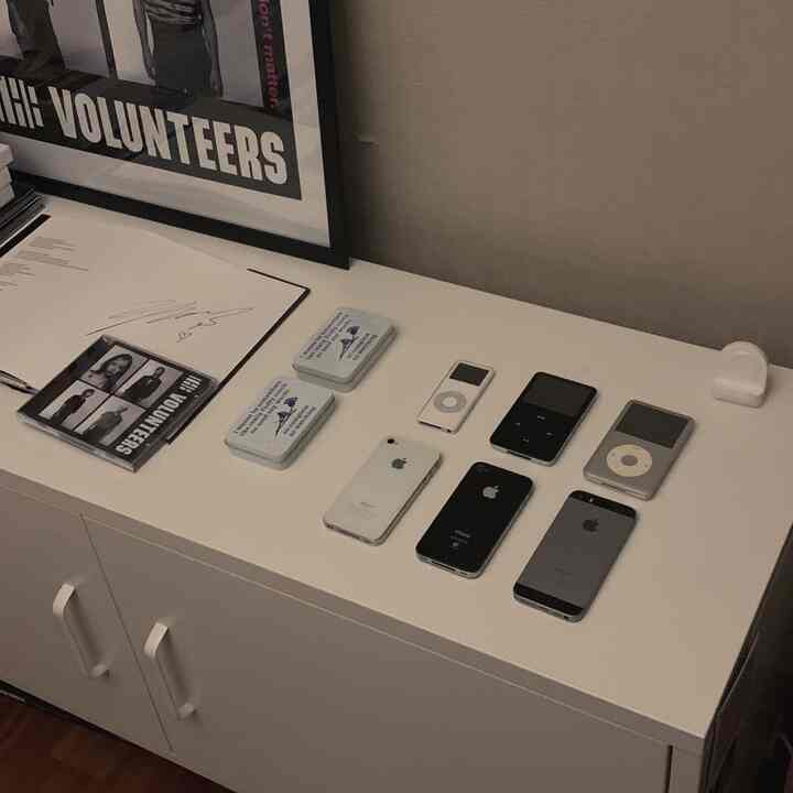 White cabinet top featuring neatly arranged Apple iPhones and iPods in a clean home gallery space