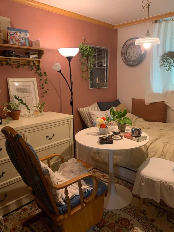 Cozy single household living-bedroom with warm natural tones, vintage furniture, dining table, rug, and floor lamp blending harmoniously