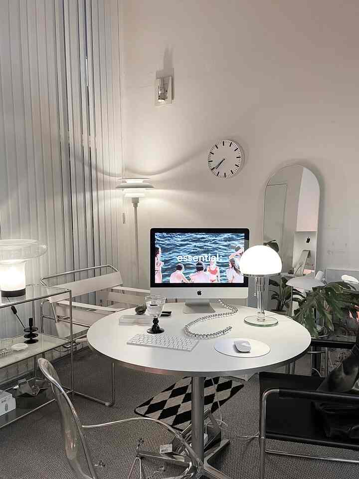 白を基調としたワンルームのホームオフィス空間、丸テーブルと全身鏡、テーブルランプが配置されたモダンなインテリア