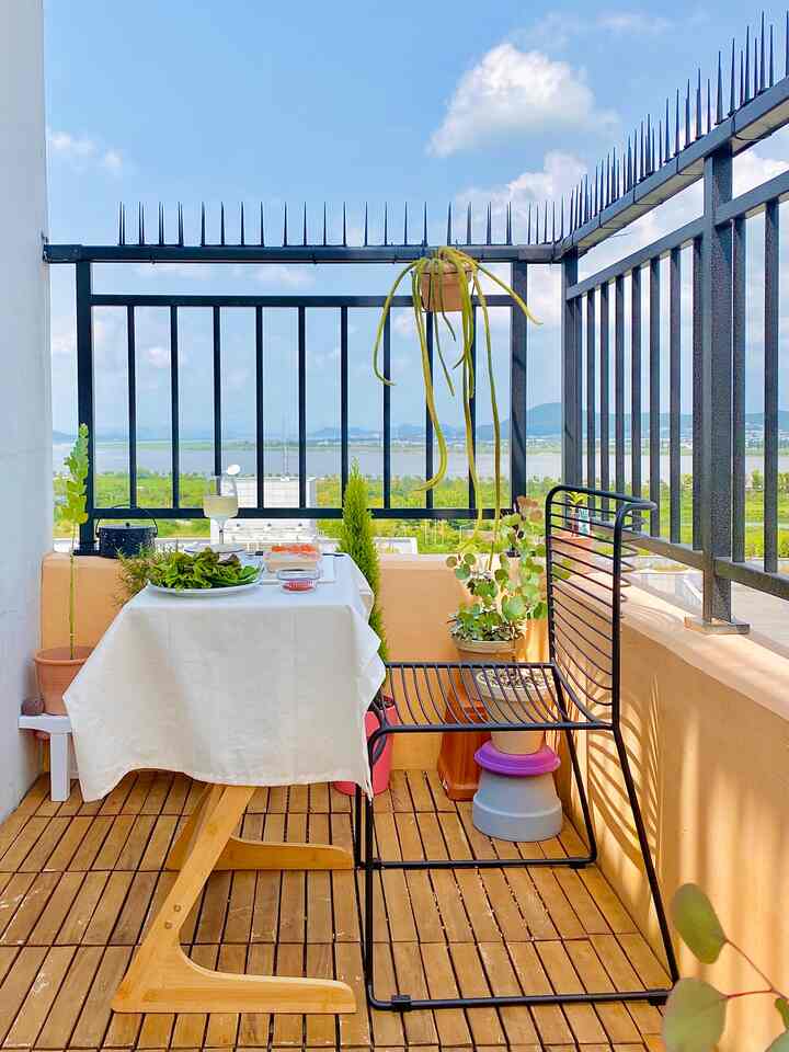 白いテーブルクロスと木目調の床が調和した、植物と屋外席のある雰囲気のよいベランダのおうちカフェ