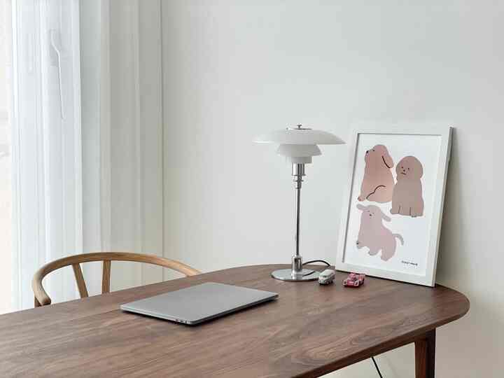 白い壁とカーテン、木製の机と椅子が配置された落ち着いた書斎兼ホームオフィス空間