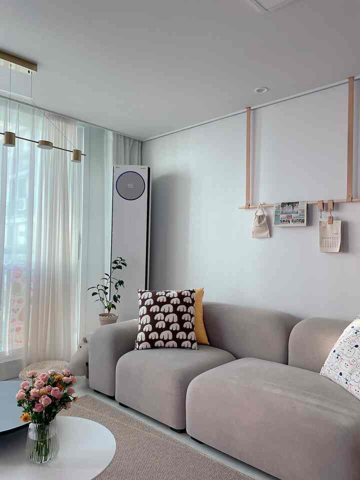 Beige and white toned living room featuring a modern sofa with cushions and a potted plant in a cozy setting
