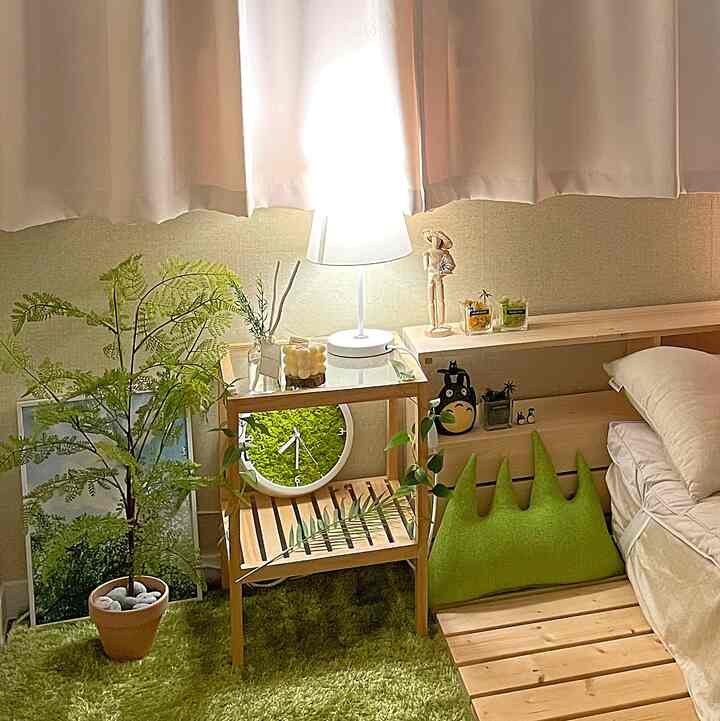 Cozy bedroom corner with natural wood tones and green plants surrounding a wooden nightstand and bed