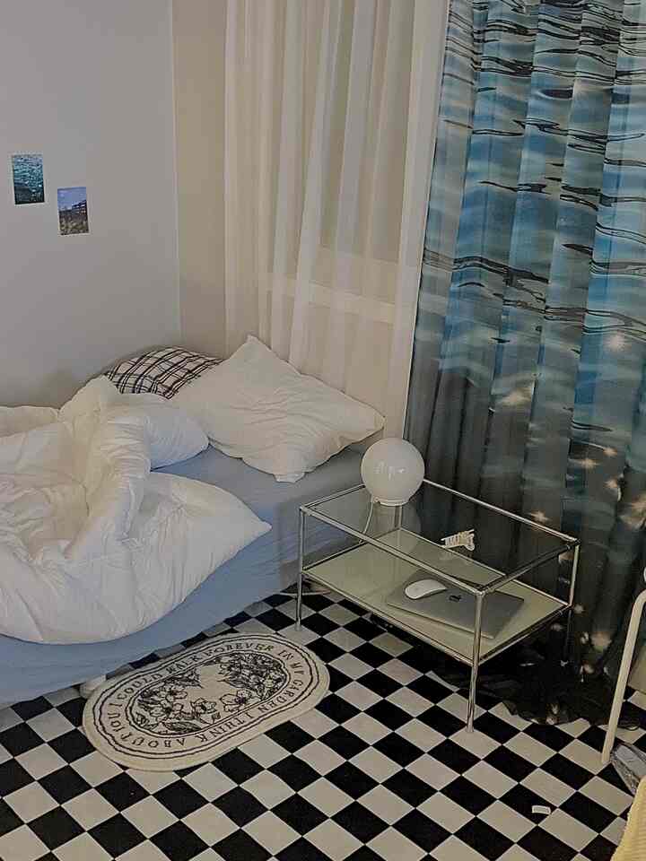 青と白のトーンの寝室、シングルベッドとメタルのサイドテーブルが配置されたコンパクトな部屋