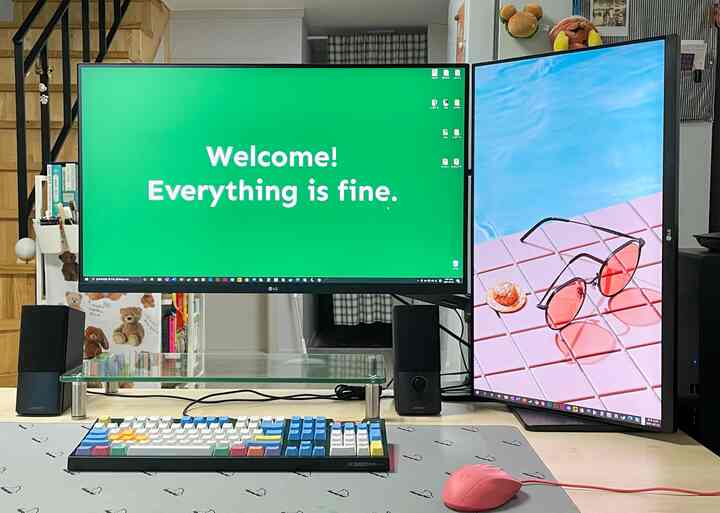 White and blue-toned studio apartment home office featuring dual monitors and a gaming keyboard in a modern computer workspace