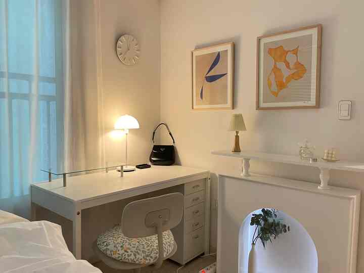 A study space in white and natural tones featuring a desk, chair with patterned cushion, and minimalist decor creating a clean atmosphere