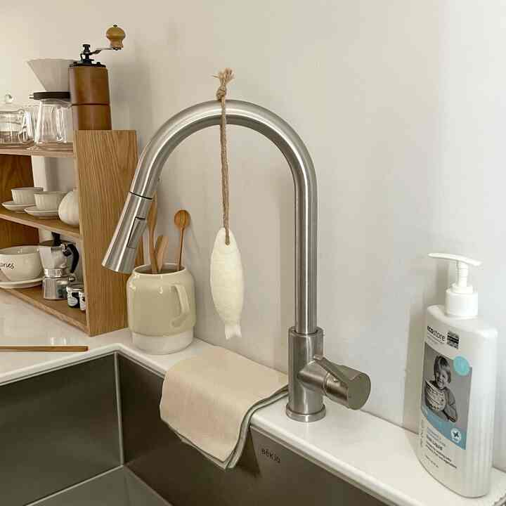Natural-toned kitchen featuring stainless steel sink and faucet, wooden shelf with coffee accessories creating a cozy atmosphere