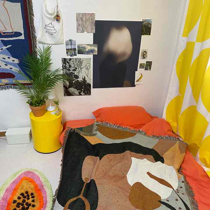 Warm bedroom with orange bedding and yellow accents, featuring wall art collage and a green plant for a natural vibe